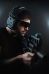 Man holding a rifle while wearing EXO Pro Elite earmuffs and SWITCH ballistic glasses